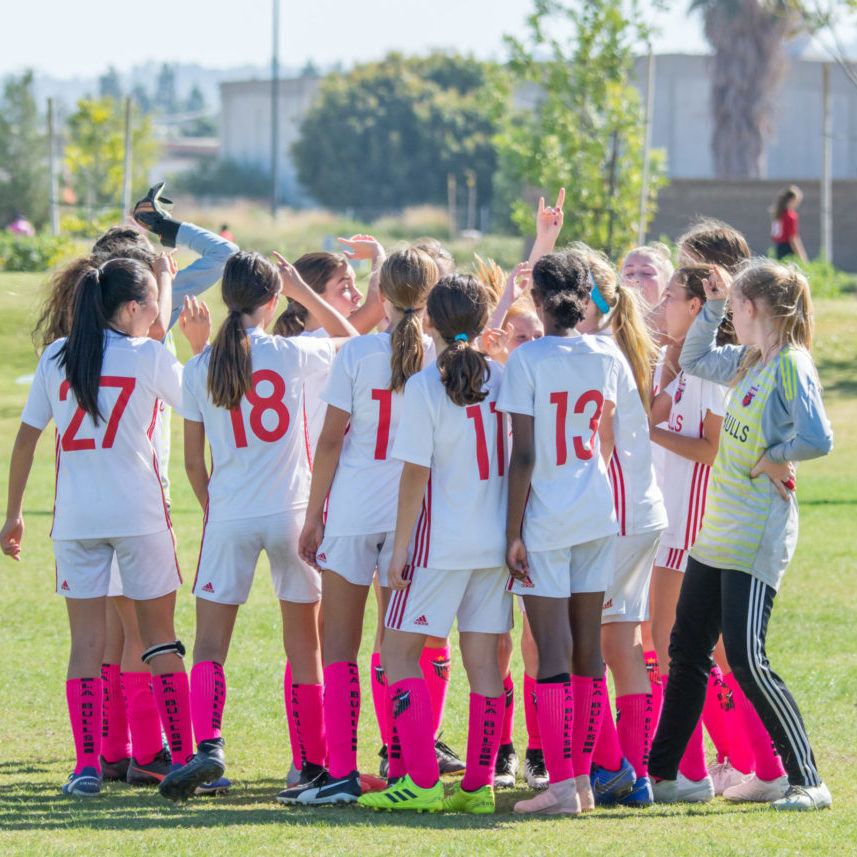 Girls huddled with pink socks Girls soccer team huddled with pink socks